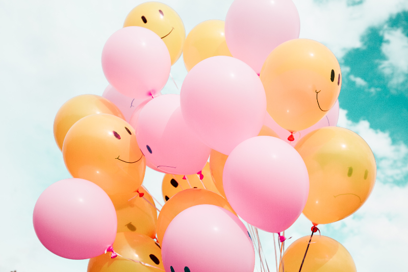 a large bunch of pink and orange balloons with happy and sad faces