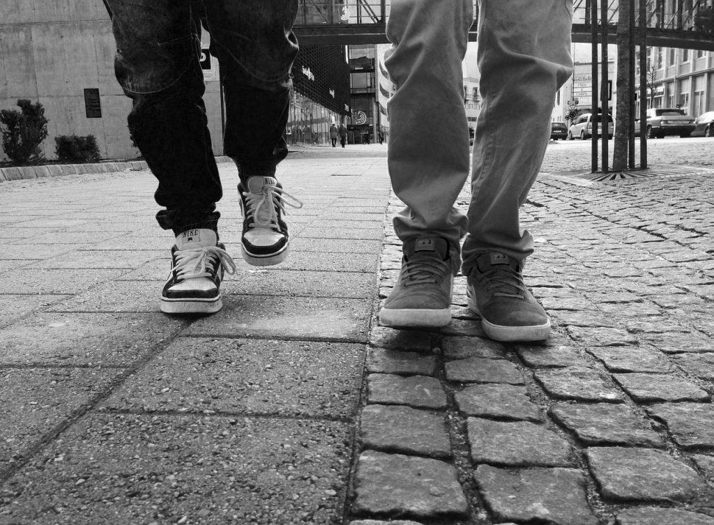 black and white photo of two pairs of legs walking along an urban pavement