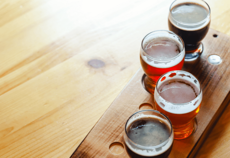 a photo of four beers on a wooden beer flight
