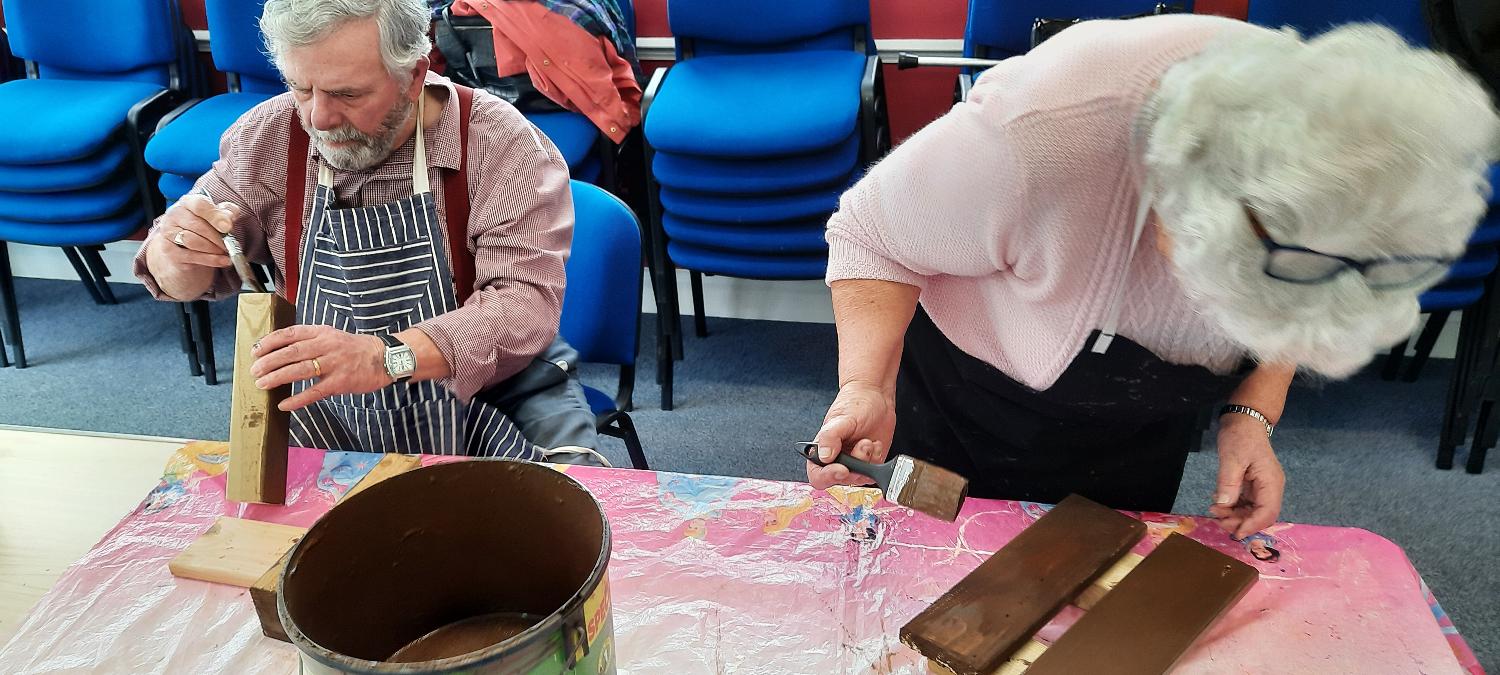 two SSW members using wood stain to paint wood