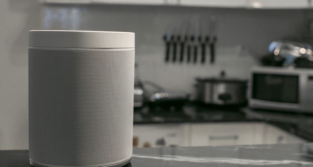 photo of a smart speaker sat on a surface in a kitchen