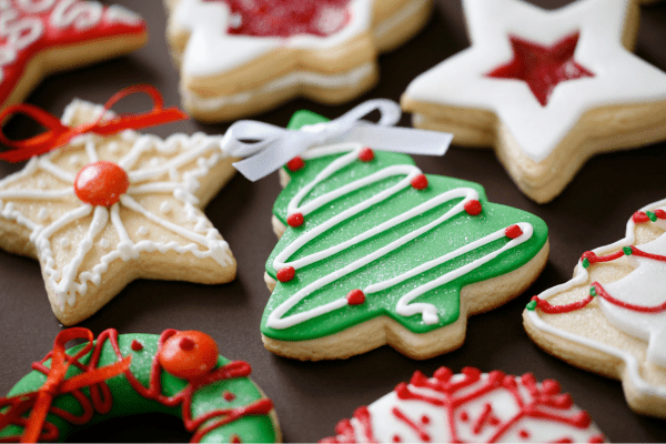 a photo showing shaped biscuits decorated with festive patterns including stars and Christmas trees. The icing is green, red and white and there are metallic spherical decorations too.