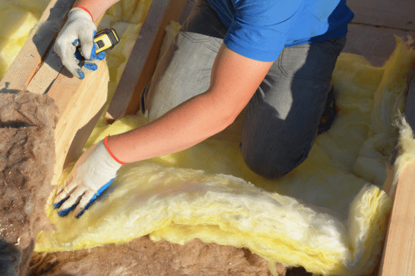 a photo of someone installing insulation into a roof