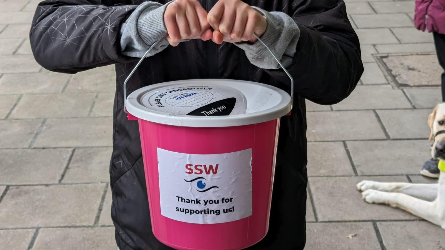 An image of someone holding an SSW donation bucket