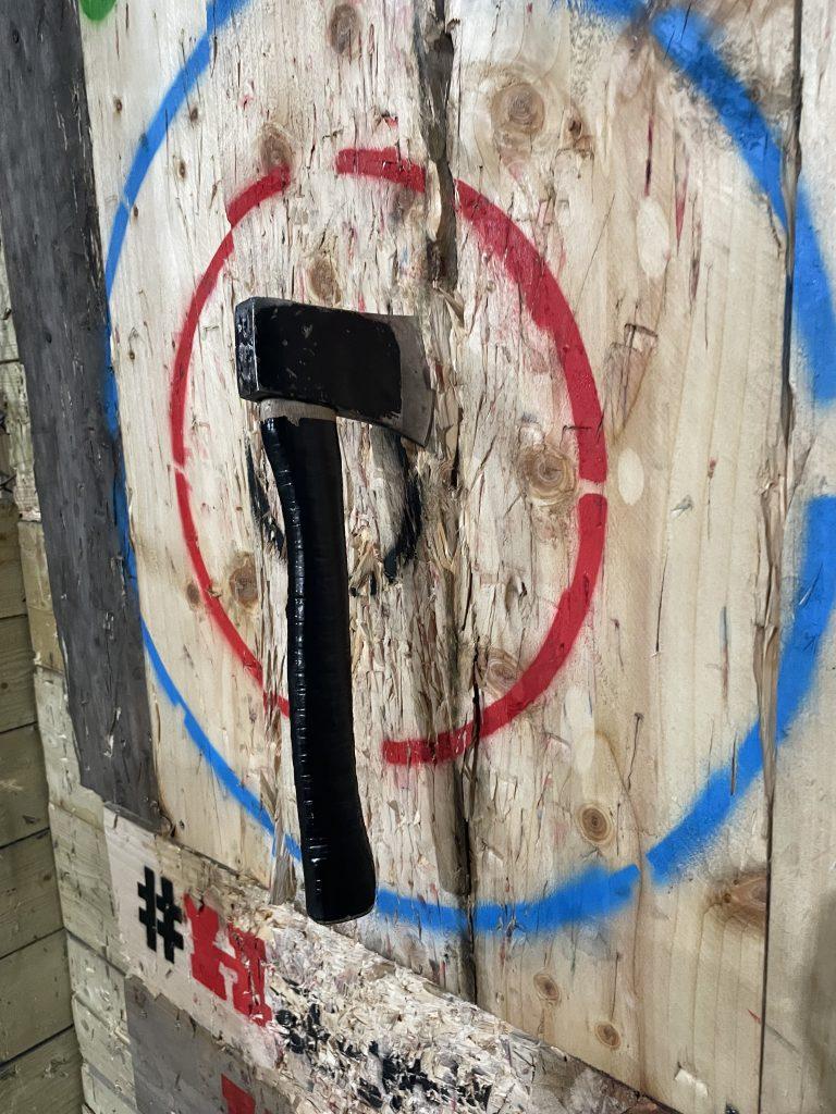 A hatchet stuck in the bullseye of a wooden board
